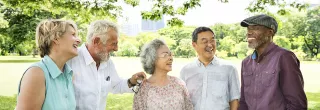 Five people laughing outside in park-like setting