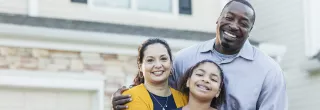 Diverse family of mother, father, daughter in front of single family home